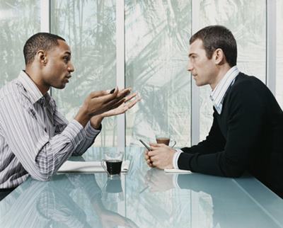 Two Businessmen Sitting and Talking Face to Face in a Meeting