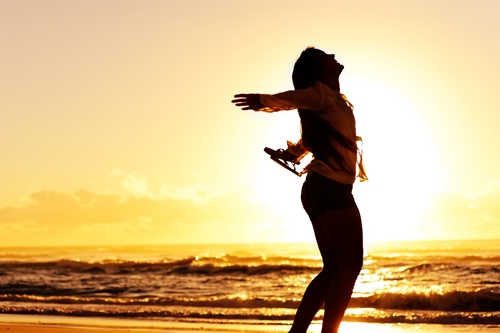 carefree woman dancing in the sunset on the beach. vacation vitality healthy living concept